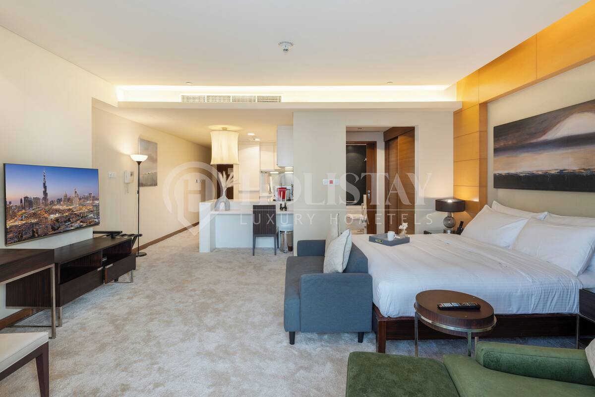 A modern hotel room with a large bed, a desk, a sofa, and a TV.