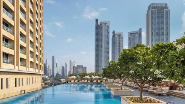 A swimming pool with lounge chairs and umbrellas, surrounded by tall buildings. - Holistay Luxury Homes,  Down Town Direct Access Dubai Mall (Dubai)