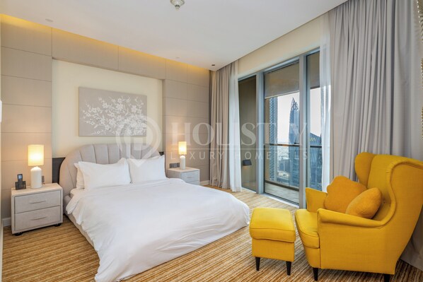 Une chambre d’hôtel moderne avec un grand lit, un fauteuil jaune et une vue sur la ville par la fenêtre.