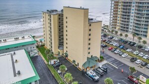 A high-rise hotel with a parking lot and a view of the beach.