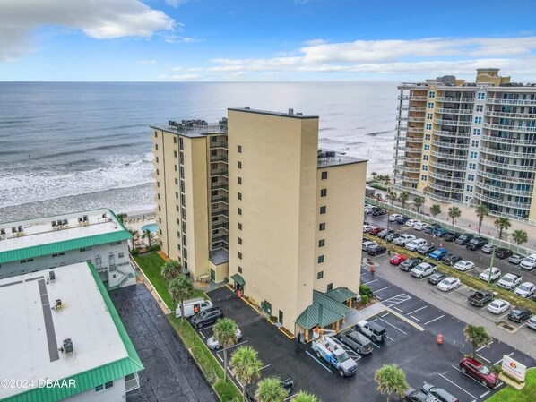 Un hotel de gran altura con estacionamiento y vistas a la playa.