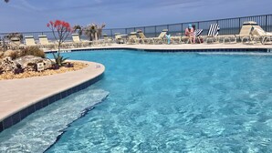 A clear blue pool with a no entry sign, surrounded by lounge chairs and palm trees.