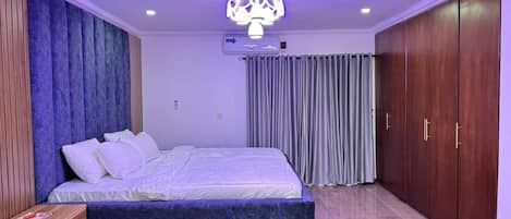 A bedroom with a bed, a nightstand, a wardrobe, and a ceiling light fixture.