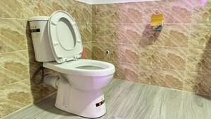 Un inodoro con asiento y tapa blancos, un tanque con panel de control y un bidé instalado en la pared.