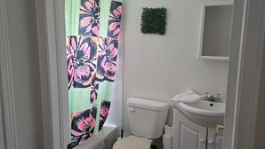 A bathroom with a toilet, sink, and shower curtain. - Charming 2-bedroom cottage in Bancroft with AC, WiFi. Enjoy your stay (Bancroft)
