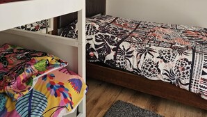 A bunk bed room with a patterned bedspread, a framed picture on the wall, and a window with blinds. - Charming 2-bedroom cottage in Bancroft with AC, WiFi. Enjoy your stay (Bancroft)