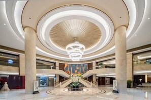 A spacious lobby with a central atrium, multiple levels, and a grand chandelier. - Oriental Hotel (Quzhou)