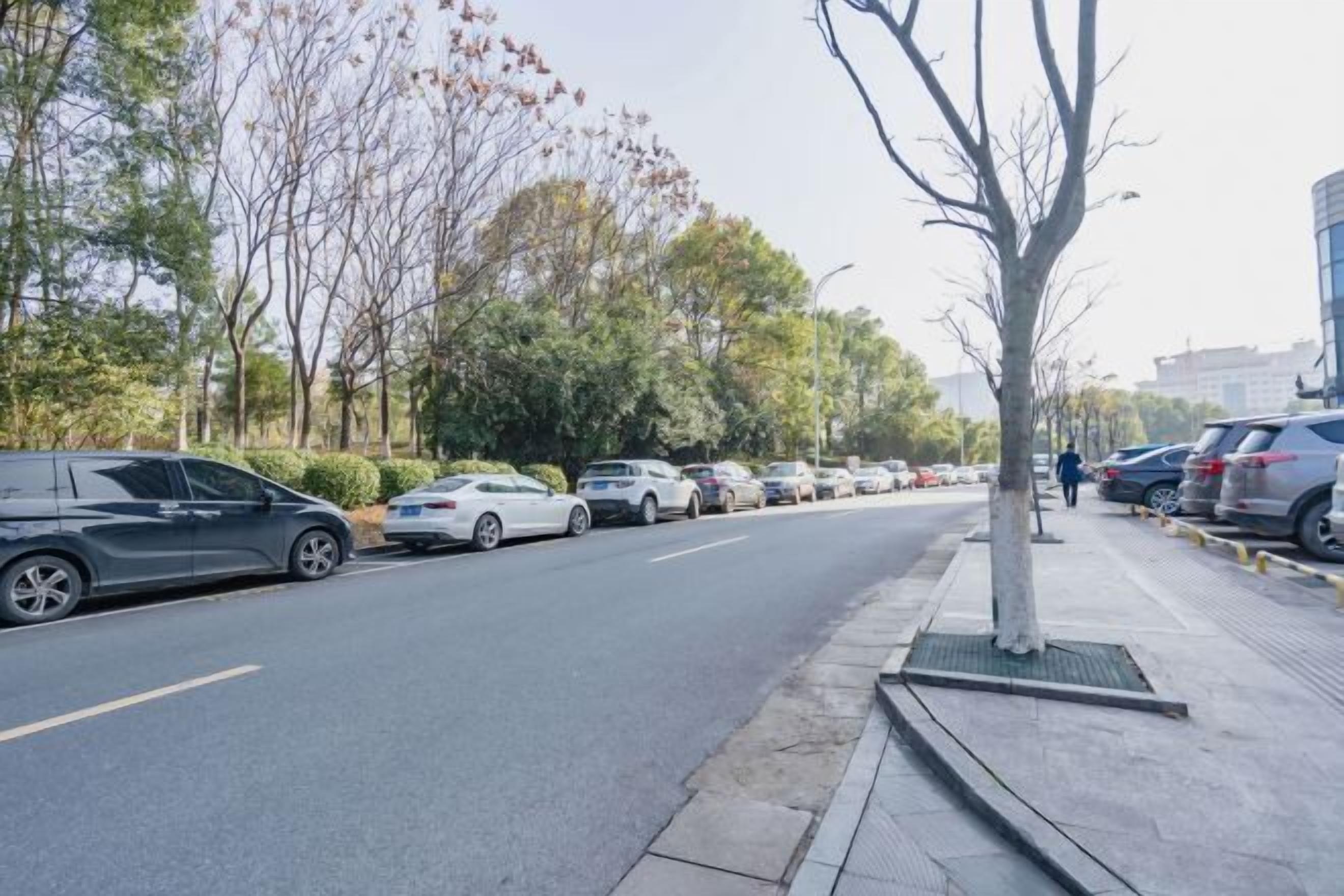 A parking lot with cars parked along the side of a road.