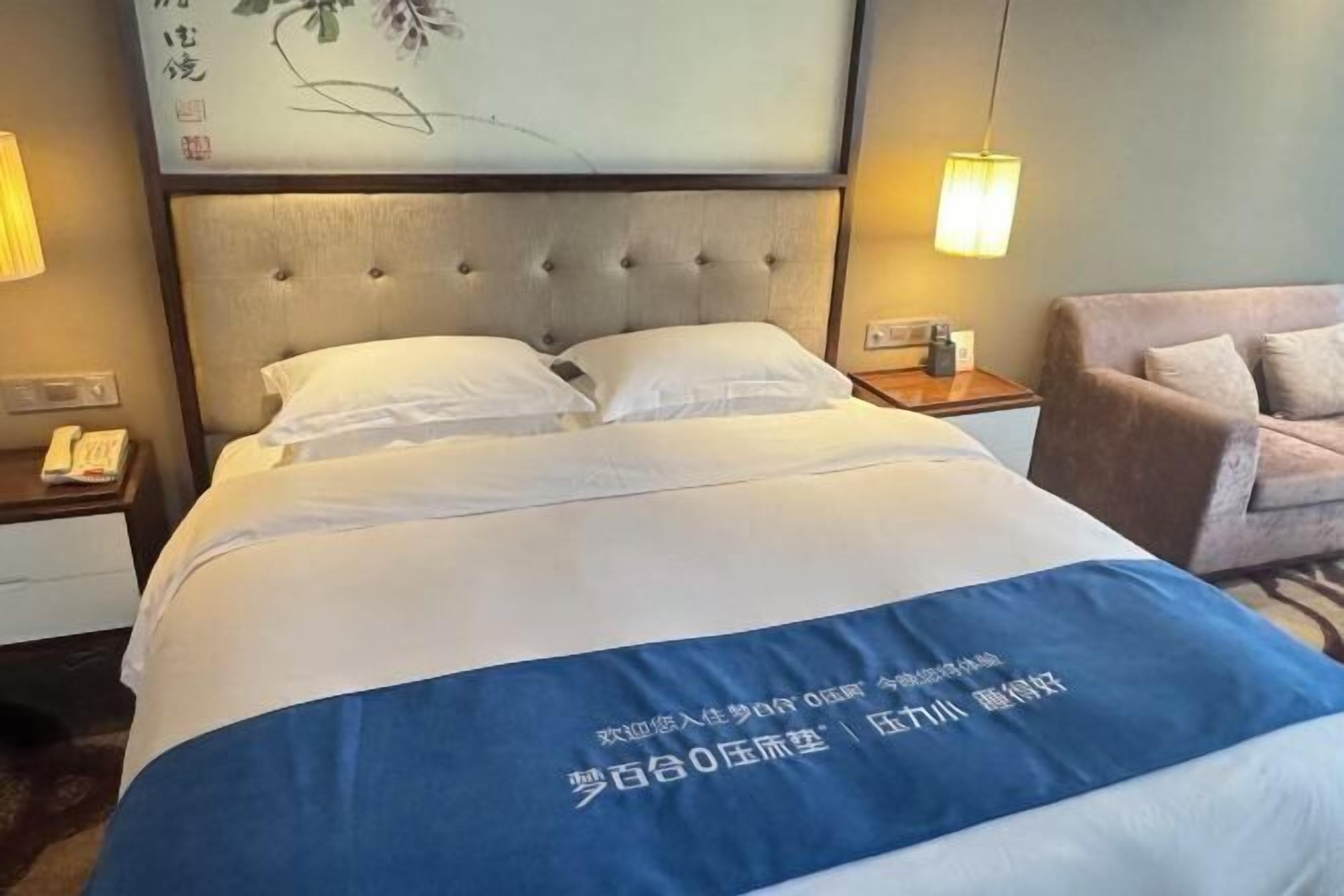 Una habitación de hotel con cama, mesitas de noche, lámpara y sofá.