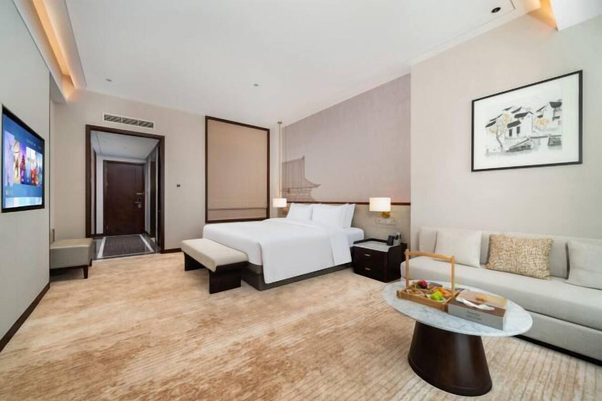 Habitación de hotel con cama, mesita de noche, lámpara, sofá y una mesa de centro.