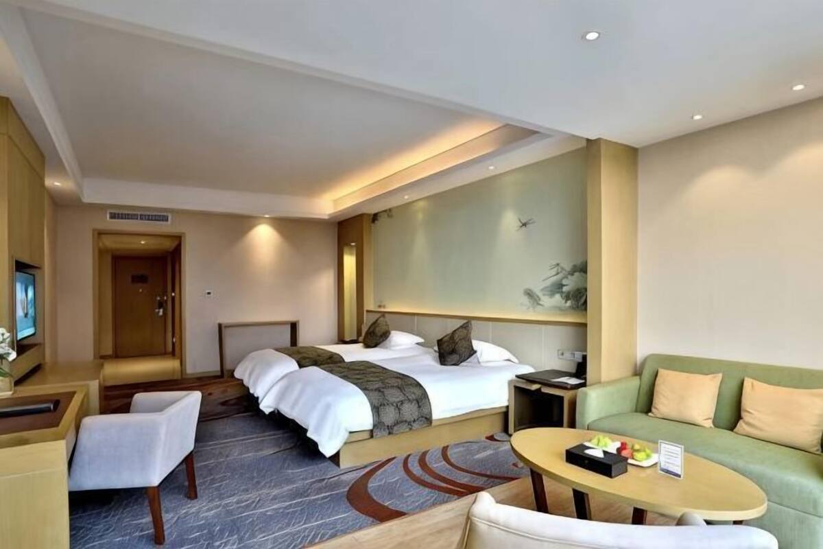 Una habitación de hotel con una cama, un sofá, un escritorio y un televisor.