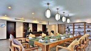 Un espace repas comprenant une longue table en bois, plusieurs chaises et des lampes suspendues.