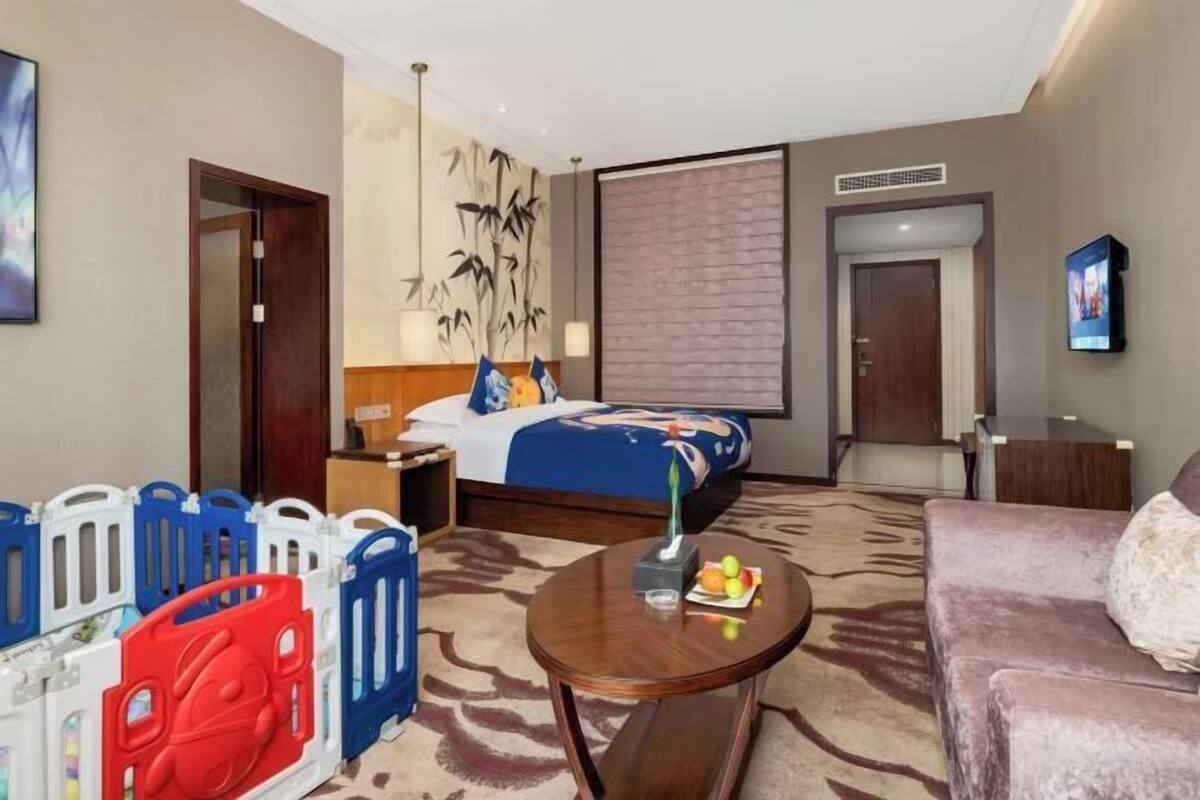 Una habitación de hotel con una cama, una mesita de centro, un sofá, un televisor y una pared decorada con una obra de arte de bambú.