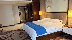 Une chambre d’hôtel avec un grand lit, une table de chevet, une lampe et un mur décoré d’œuvres d’art.