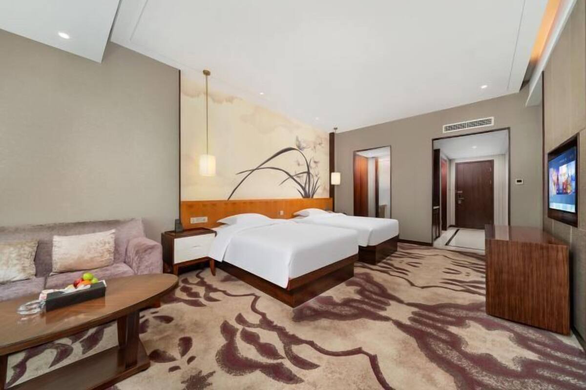 Una habitación de hotel con cama, sofá, televisor y escritorio.