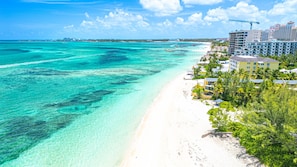 Un hotel frente a la playa con una arena dorada y aguas turquesas cristalinas.