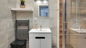 Une salle de bain moderne avec une douche à parois de verre, un lavabo blanc et un porte-serviettes.