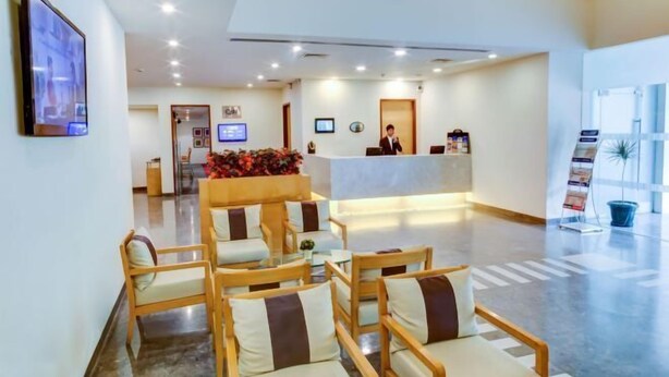 A hotel lobby with a reception desk, seating area, and a large window. - Radha Hometel Bengaluru (Bengaluru)