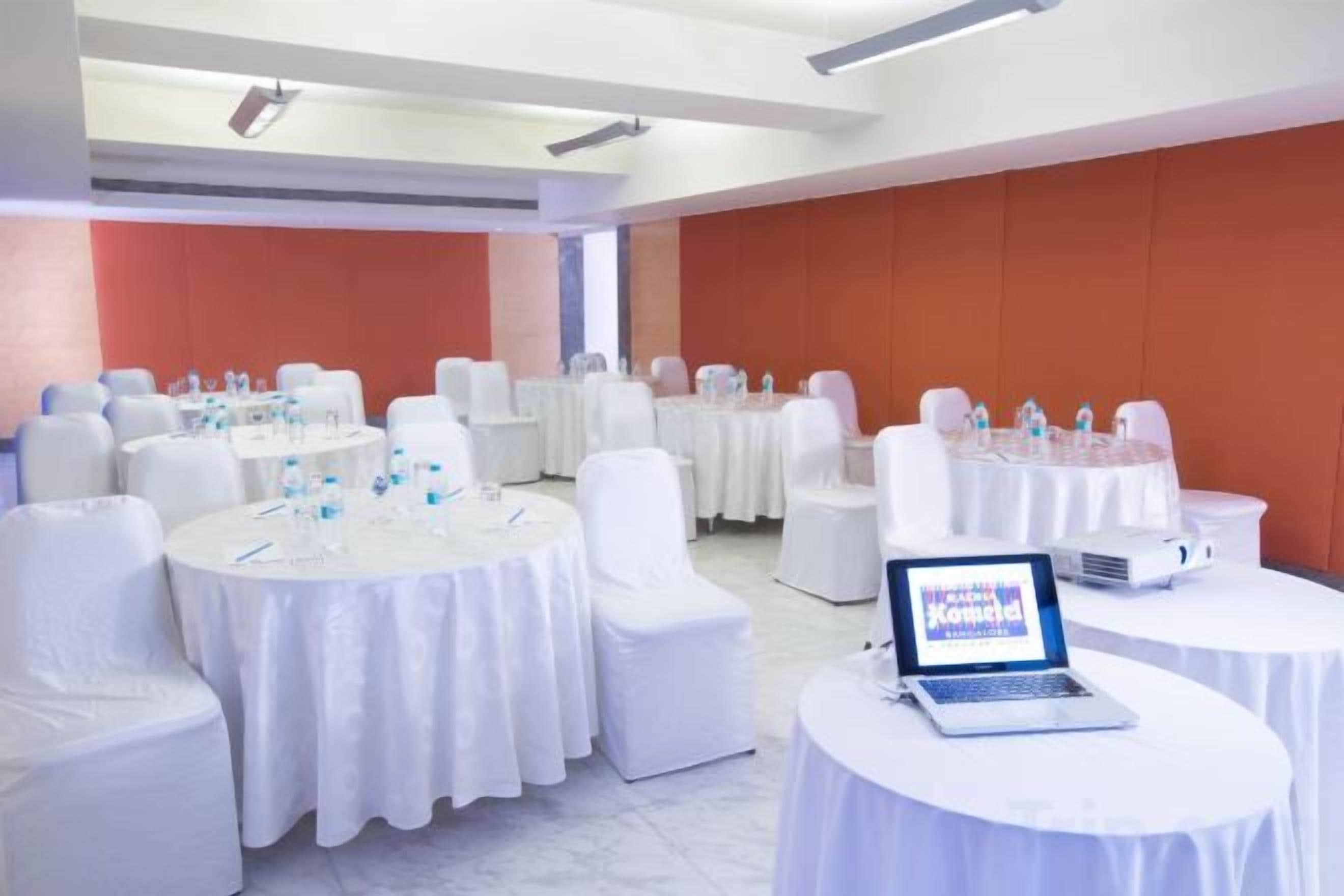 A conference room with round tables, white chairs, and laptops.