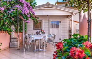 Relax in style on this charming patio, complete with a table for two, comfortable seating, and a serene garden setting.