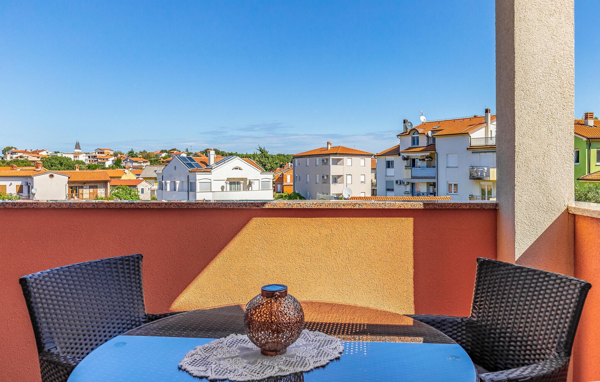 A terrace with a table and chairs, a decorative vase, and a view of residential buildings.