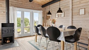 A wooden cabin with a dining area featuring a table, chairs, and a fireplace. - Stunning home in Aabenraa (Aabenraa)