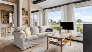 A spacious living room with a large window, a wooden ceiling, and a sofa with cushions. - Stunning home in Aabenraa (Aabenraa)