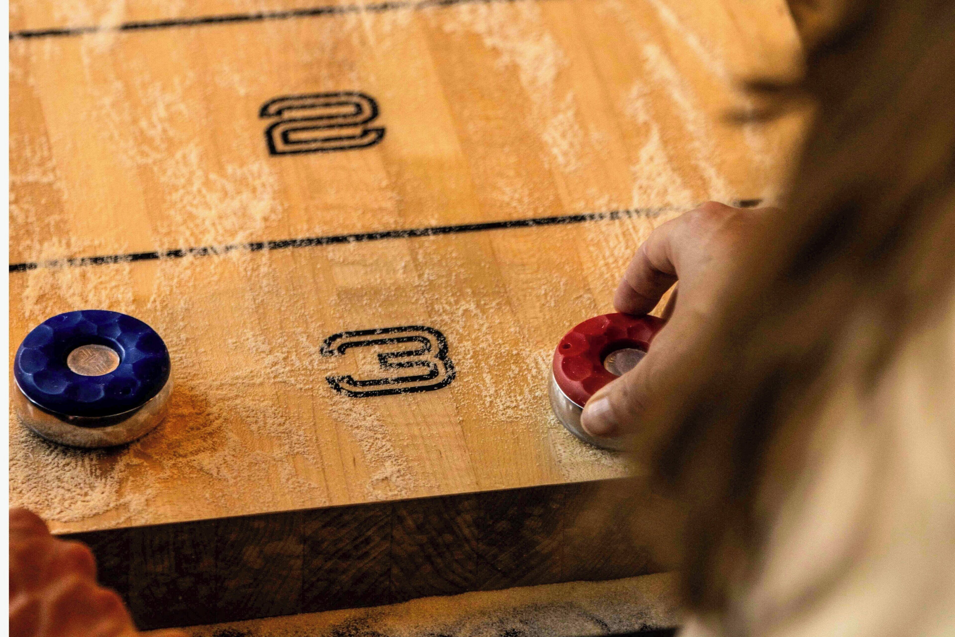 Detalhe de uma mesa de jogo de bocha de madeira com áreas de pontuação numeradas.