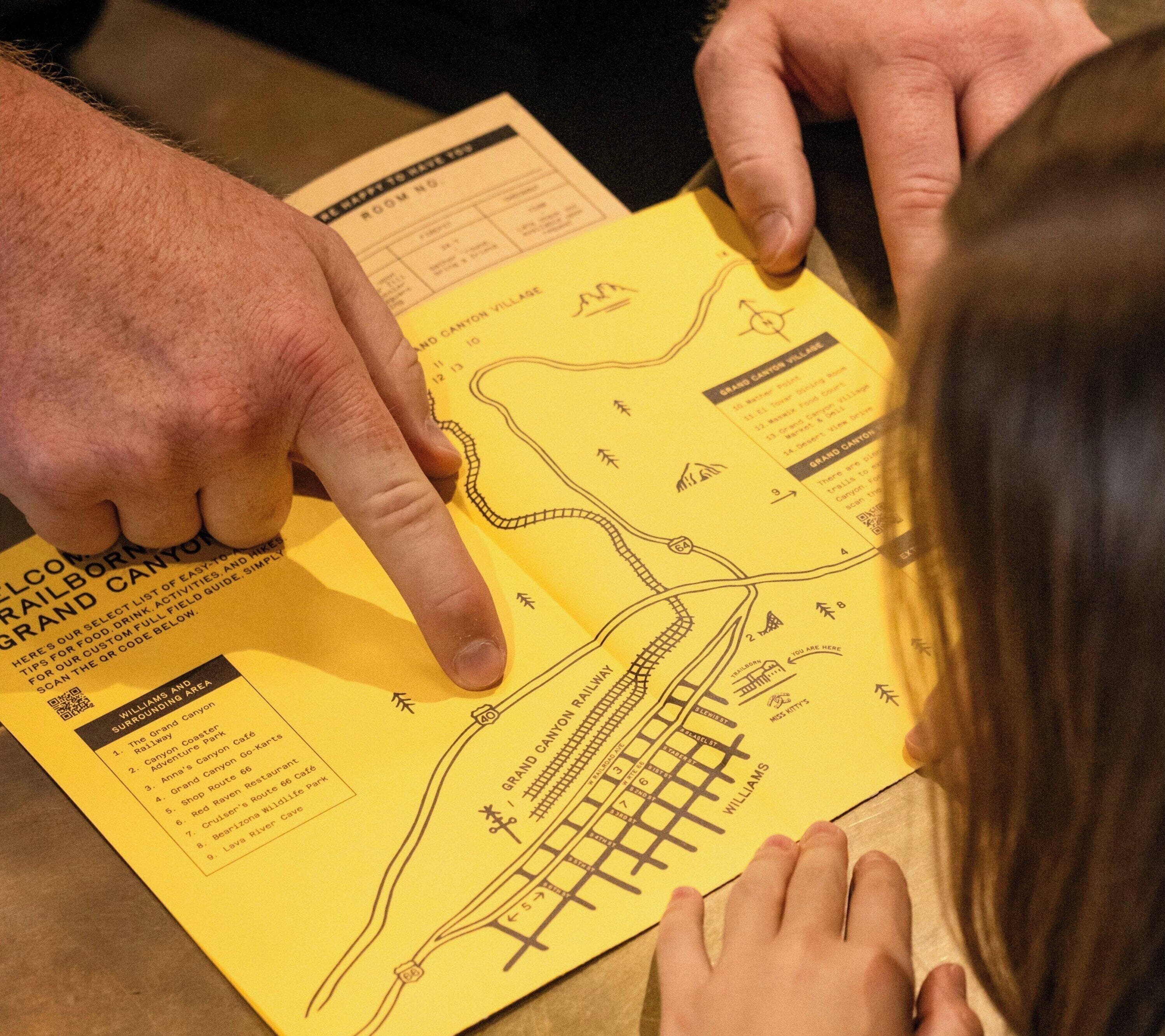 A person pointing at a yellow map with a railway layout and surrounding area names.