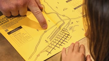 A person pointing at a yellow map with a railway layout and surrounding area names.