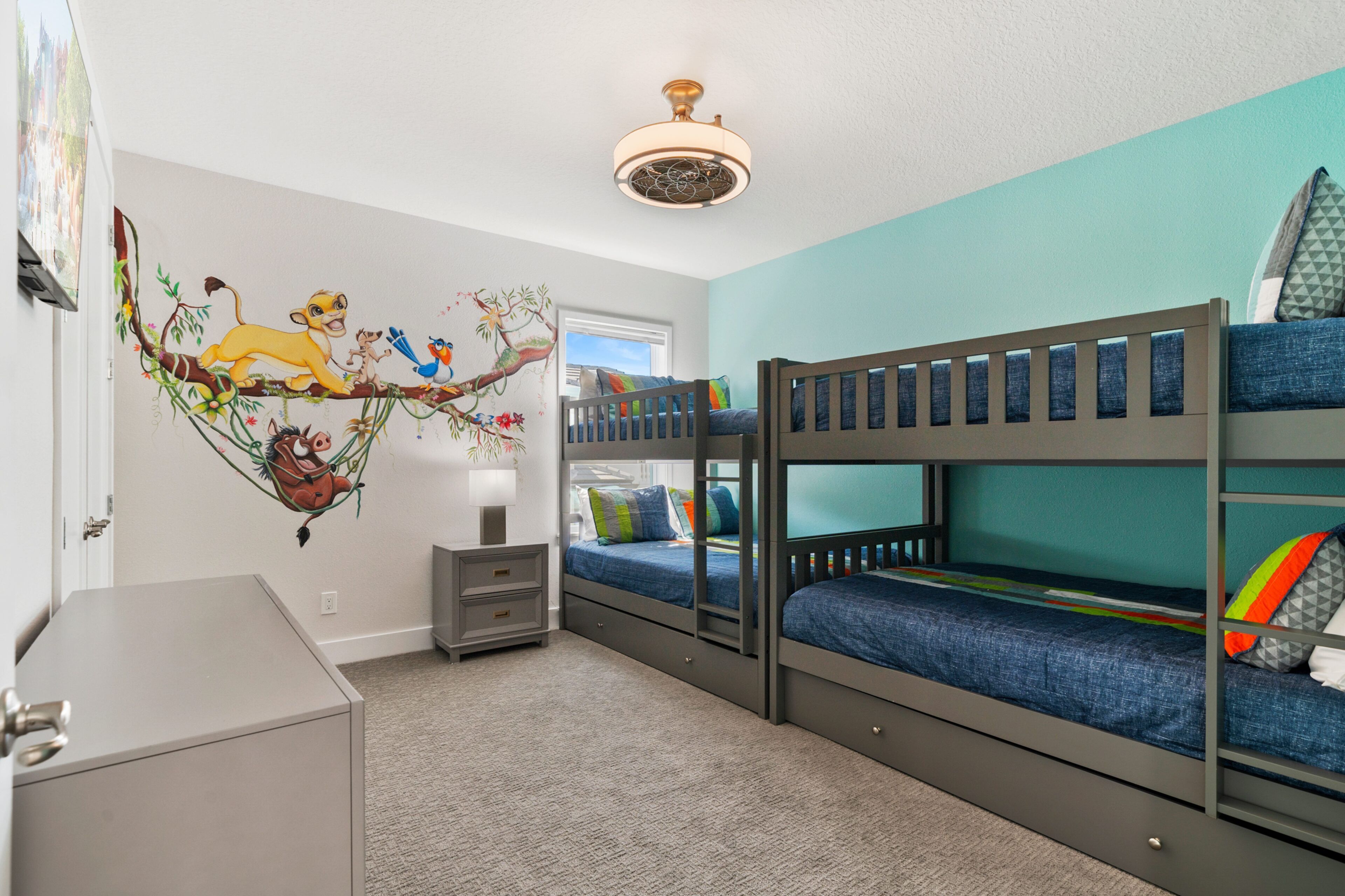 A child's bedroom with bunk beds, a ceiling fan, and a wall mural.