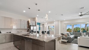 A modern kitchen with a large island, stainless steel appliances, and pendant lighting. - Jacks Club Serenity Villa-TB026 (Kissimmee)