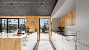 Une cuisine moderne dotée d’un grand îlot central, de touches de bois et offrant une vue sur l’extérieur.