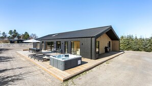 Une maison moderne dotée d’un jacuzzi, d’un espace salon extérieur et d’une grande terrasse.