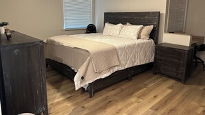 Een slaapkamer met een bed, een dressoir, een bureau en een plafondventilator.