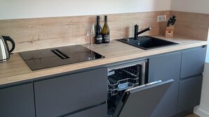 Una cocina moderna con armarios de madera, un lavabo negro y un lavavajillas integrado.