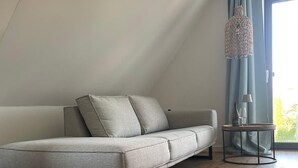 Una sala de estar moderna con un sofá gris, una mesita auxiliar y una lámpara colgante.