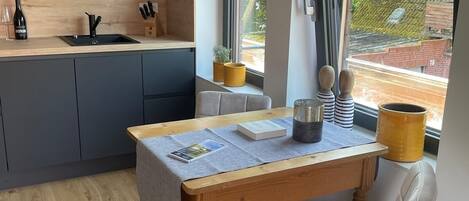 A modern kitchen with a wooden countertop, a sink, and a window with a view of greenery.