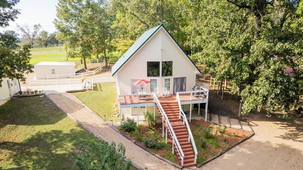 Una casa a un piano con un portico coperto e una scala in legno che conduce a un terrazzo.