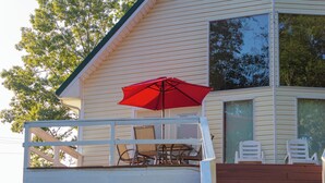 Una casa con un balcone, un ombrellone rosso e mobili da giardino.