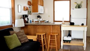 Um espaço compacto com cozinha compacta, área de refeições e sofá com almofadas.