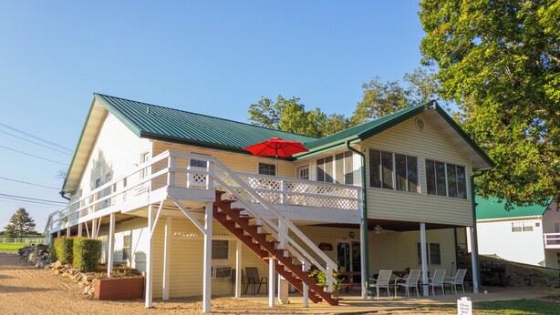 A two-story building with a covered porch and a staircase leading to the upper level. - "The Lodge" GREAT FOR GROUPS & Walk-in Norfork River Access in Norfork, AR (Norfork)