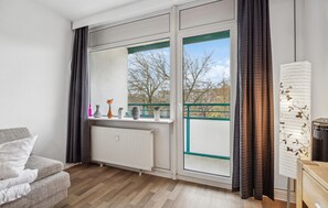 Relax in a spacious room with a sliding glass door leading to a balcony offering views of the surrounding landscape.