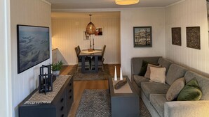 A living room with a gray sofa, a dining table with chairs, a chandelier, and framed artwork on the walls. - 2 bedroom nice apartment in Vegårshei (Vegårshei)