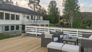 A wooden deck with wicker furniture and a white railing. - 2 bedroom nice apartment in Vegårshei (Vegårshei)