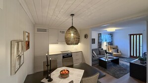 A modern living room with a sofa, coffee table, and a dining area with a table and chairs. - 2 bedroom nice apartment in Vegårshei (Vegårshei)