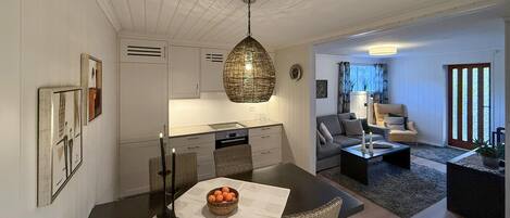 A modern living room with a sofa, coffee table, and a dining area with a table and chairs.