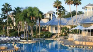 A swimming pool with lounge chairs and palm trees, surrounded by buildings with a resort-like appearance. - Fantastic condo in Orlando; fully equipped kitchen, washer/dryer, WiFi (Orlando)