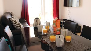 A hotel room with a dining table set with breakfast items, a sofa, and a TV on the wall. - Cozy apartment in Torre Pacheco with WiFi (Torre Pacheco)