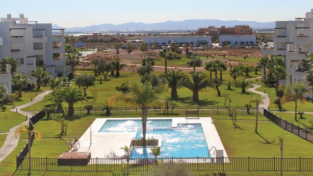 A pool area with a rectangular pool, surrounded by palm trees and a fence. - Cozy apartment in Torre Pacheco with WiFi (Torre Pacheco)